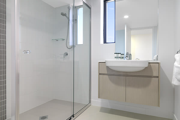 en suite bathroom of two bedroom apartment at Oaks Carlyle hotel in Mackay with large adjustable, shower, toilet and clean towels on rack