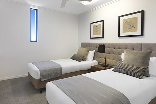 2 single beds with sidelamp in two bedroom apartment at Oaks Carlyle hotel in Mackay, Queensland, Australia