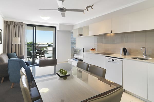 kitchen with dining room table, kettle and dishwasher in two bedroom apartment at Oaks Carlyle hotel in Mackay, QLD