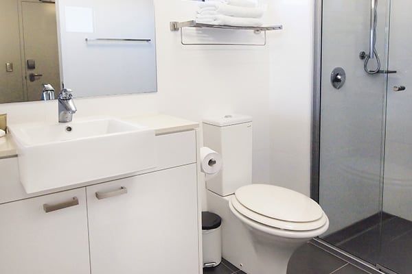 en suite bathroom with toilet and shower in studio apartment with wi-fi at Oaks Metropole Hotel in Townsville