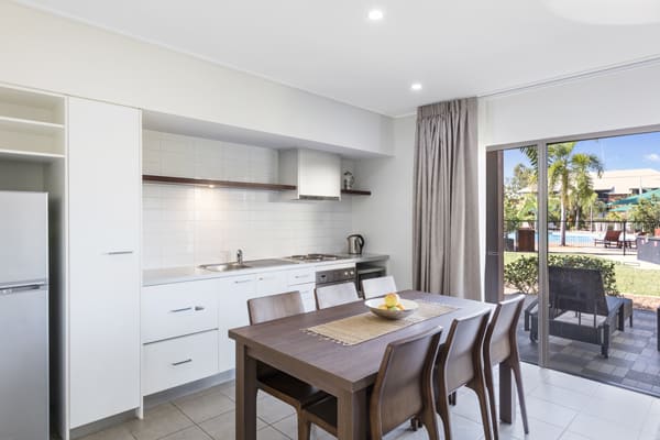 open plan kitchen with dining table, microwave, big fridge, large freezer and stove top cooker plates in 2 Bedroom Apartment at Broome hotel in Western Australia