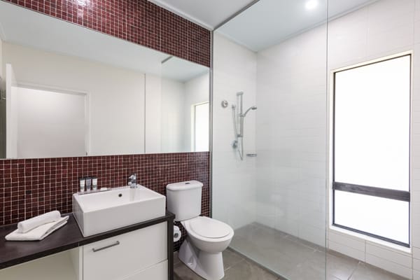 clean en suite bathroom with toilet, big shower, large mirror and fresh towels in 3 Bedroom Villa at Oaks Cable Beach Sanctuary hotel in Broome, Western Australia