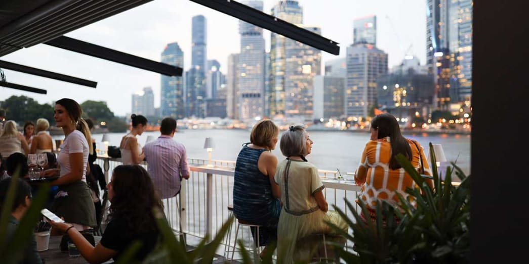 Locals sitting beneath the Story Bridge while drinking cocktails with spectacular view of Brisbane City