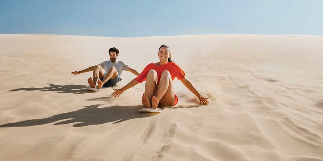 Surfing down the dunes on a hand-made sandboard Stockton Bight Sand Dunes Port Stephens New South Wales