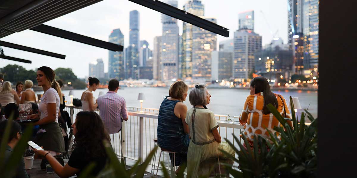 Locals sitting beneath the Story Bridge while drinking cocktails with spectacular view of Brisbane City