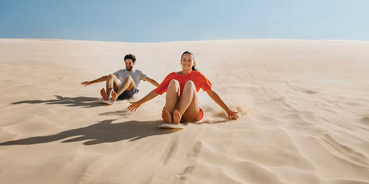 Surfing down the dunes on a hand-made sandboard Stockton Bight Sand Dunes Port Stephens New South Wales