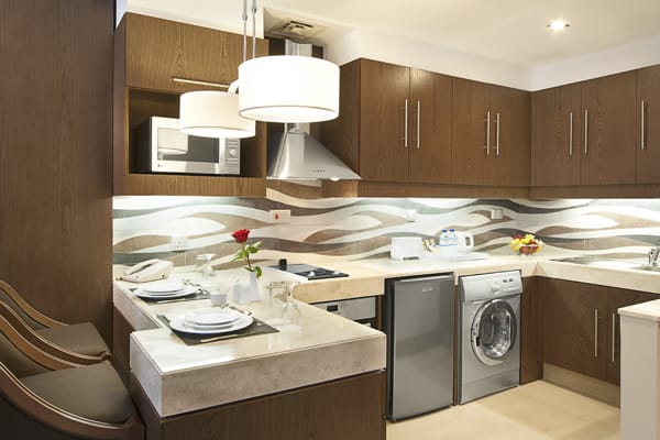 kitchen with microwave, dishwasher, fridge, kettle and toaster in Deluxe Suite of Oaks Liwa Executive Suites holiday apartments hotel in Abu Dhabi, United Arab Emirates