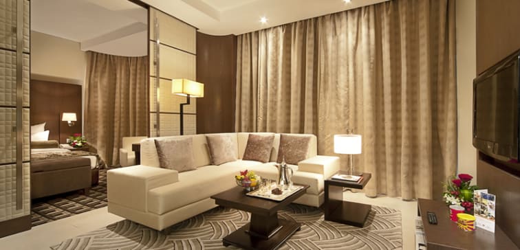 big living room with satellite TV, air conditioning and comfortable modern furniture including couches and tables and large windows with panoramic views of Abu Dhabi city in the United Arab Emirates