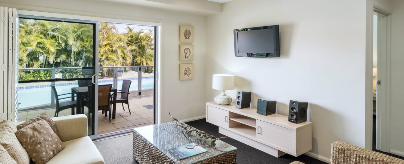 large living room area at oaks pacific blue resort hotel accommodation with balcony and swimming pool in background