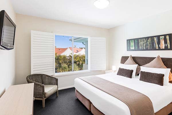 master bedroom at oaks pacific blue resort with flat screen television and views of swimming pool outside