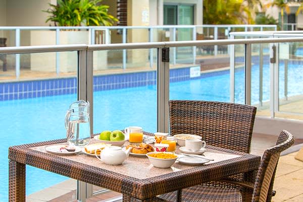 breakfast on table on balcony at oaks pacific blue resort hotel in port stephens with swimming pool in background