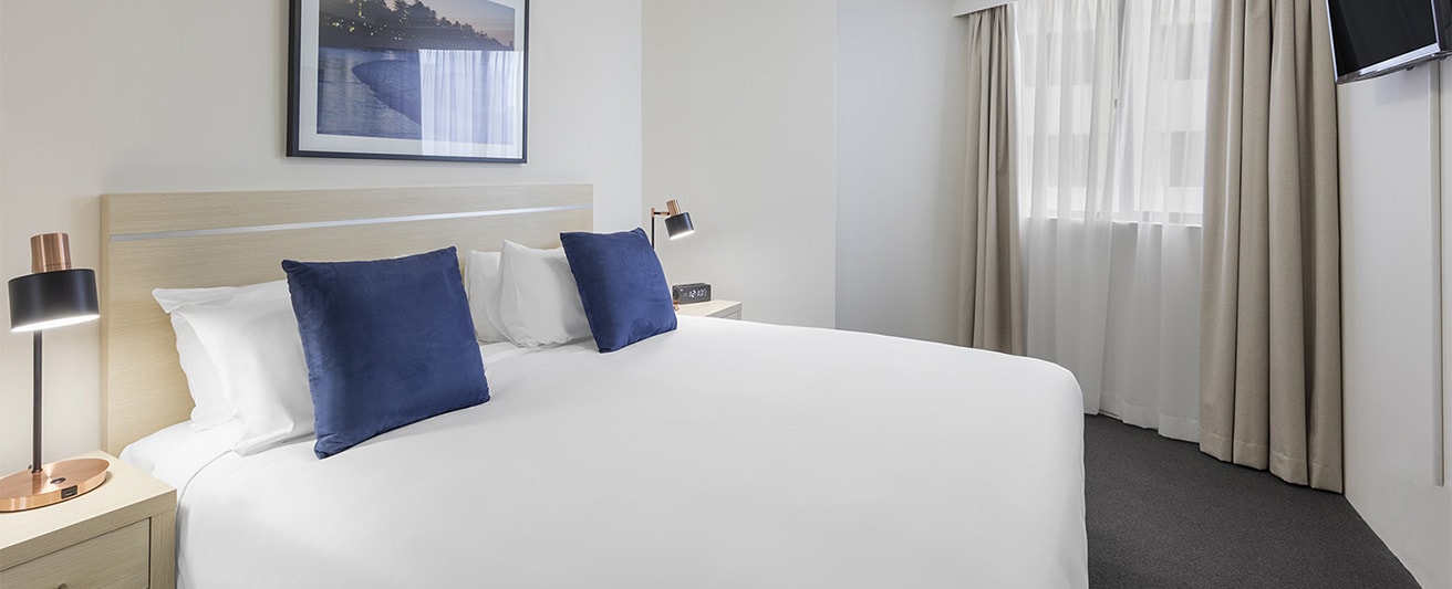king-sized bed and lamps with usb charging function on both sides of the stands in one bedroom at oaks on castlereagh sydney hotel 