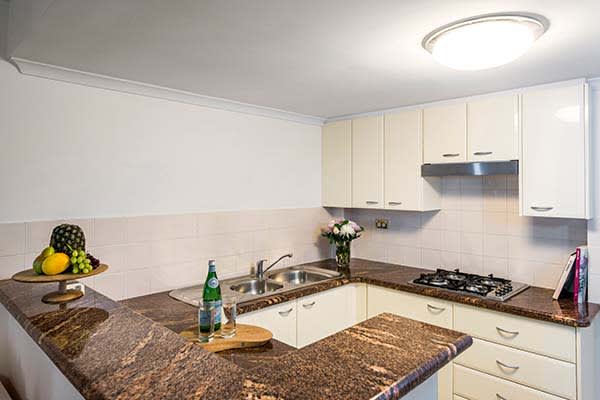 open plan kitchen in 1 bed hotel apartment Sydney cbd with marble top benches and stove top cooker