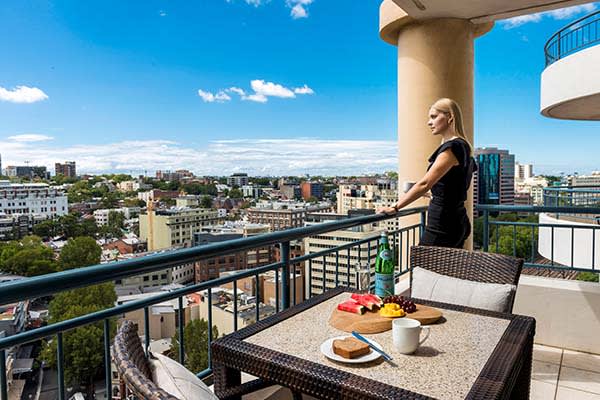 hotel visitor on balcony with breakfast on table and views of Sydney city in background