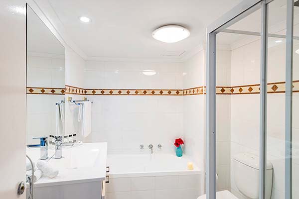 bathroom with shower and bath tub in 1 bed apartment at oaks on Castlereagh hotel in Sydney CBD