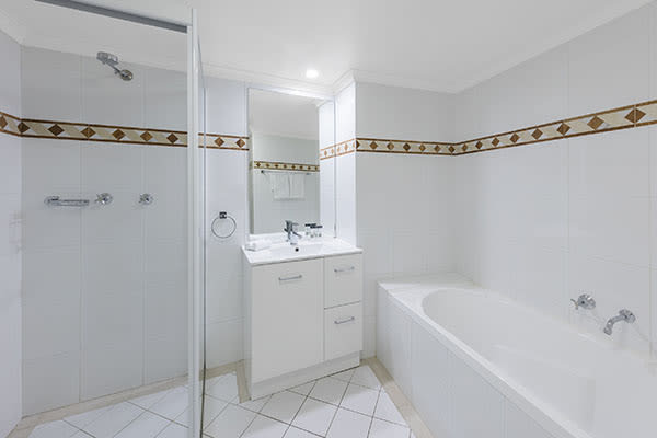 clean bathroom with a bathtub and a walk-in shower at one bedroom apartment of oaks on castlereagh sydney hotel