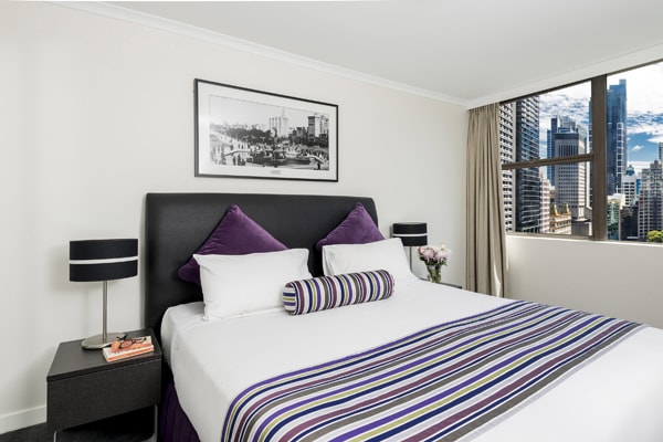 modern hotel bedroom in 2 bedroom apartment with views of Hyde Park in Sydney city