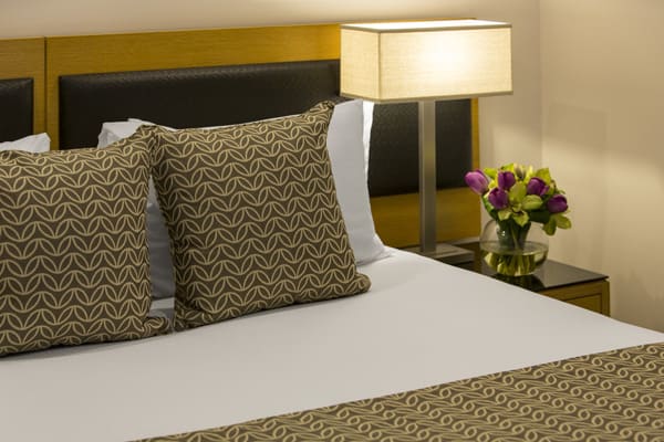close-up of clean and comfortable queen size hotel bed with fresh pillows and side tables at Oaks Elan Darwin, Northern Territory