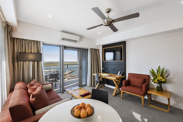 modern living room in 1 bedroom hotel apartment in Darwin hotels with TV, ceiling fan, air con and balcony at Oaks Elan Darwin in Northern Territory