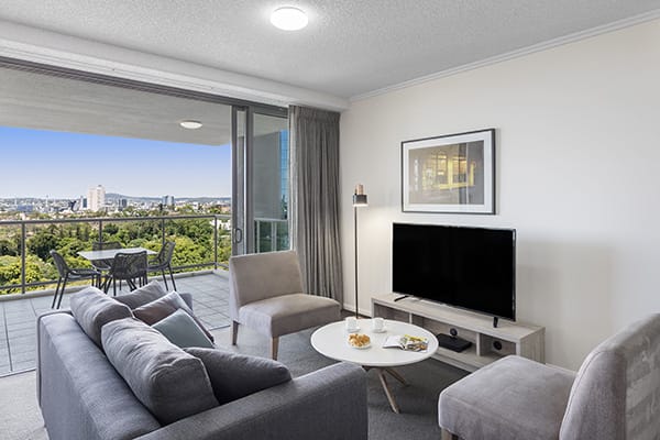 comfortable living room connected to a spacious balcony with nice brisbane city view at oaks 212 margaret 2 bedroom river view brisbane hotel