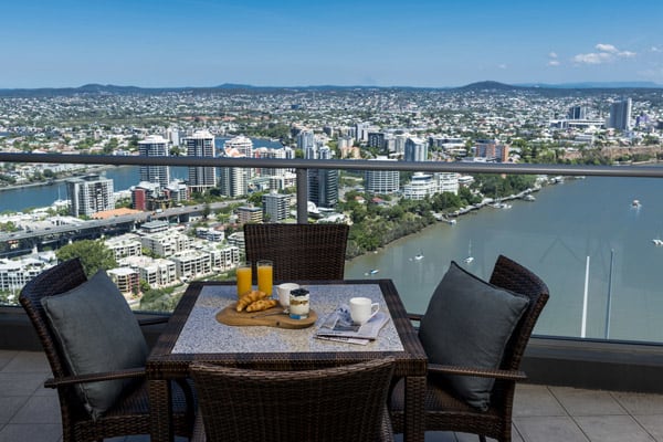 table with chairs and lunch on balcony at 1 bedroom hotel apartment at Oaks Aurora with views of Brisbane River in daytime