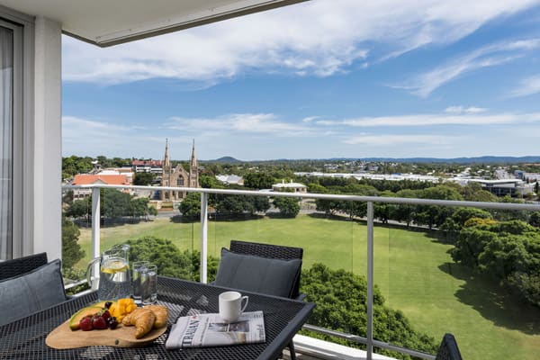 Hotels in Ipswich QLD with large 3 bedroom apartment balcony with furniture and view of park and cathedral in Ipswich, Queensland