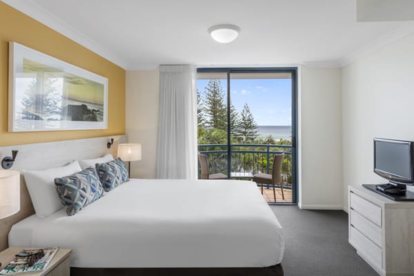 comfortable queen size bed in one bedroom apartment with balcony and television with Foxtel on Gold Coast