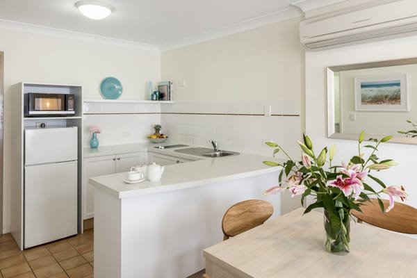 kitchen area with dining room table, fridge and microwave at Oaks Calypso Plaza hotel resort in Coolangatta near beach