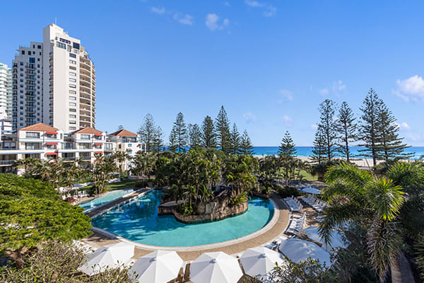 big resort swimming pool near beach in Coolangatta with blue skies and ocean in background, Gold Coast, Australia