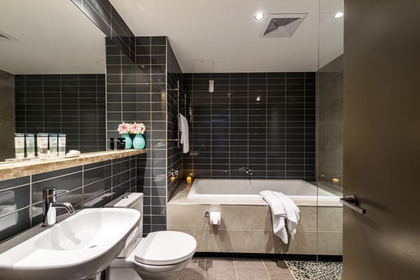 en suite bathroom with bathtub, toilet and clean towels at Mon Komo Hotel in Redcliffe, Queensland