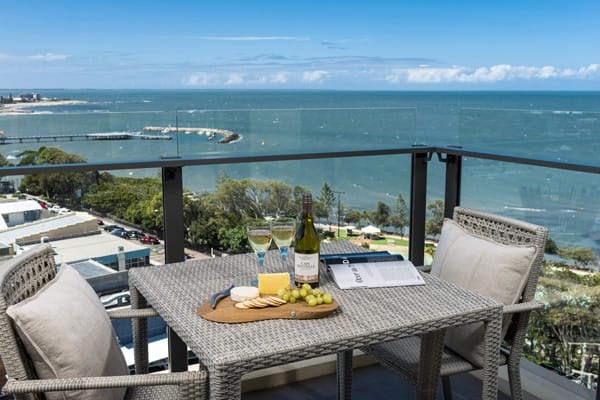 table with wine bottle, cheese and biscuits on balcony of 3 bedroom apartment with views of ocean at Oaks Mon Komo Hotel in Redcliffe