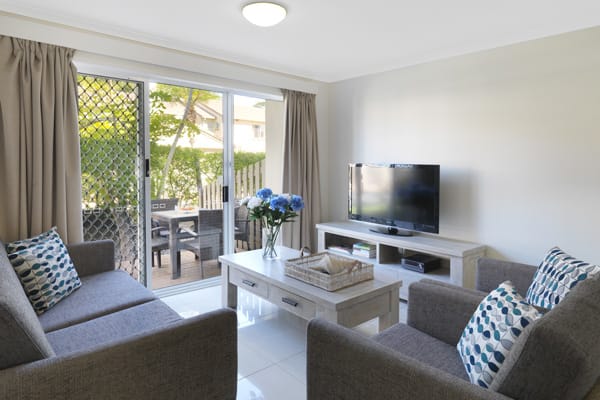living room with television with Foxtel and Wi-Fi and private balcony with furniture in 3 bedroom villa at Oaks Oasis Resort in Caloundra on Sunshine Coast, Queensland, Australia