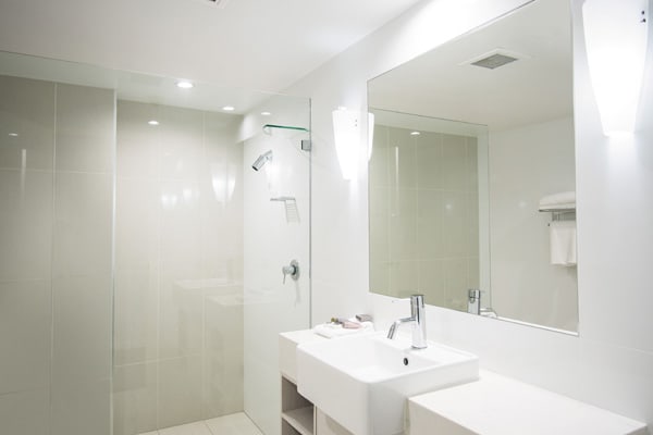 en suite bathroom with large mirror, toilet, shower and air conditioning in Executive Family hotel room at Oaks Oasis Resort in Caloundra on Sunshine Coast, Queensland, Australia