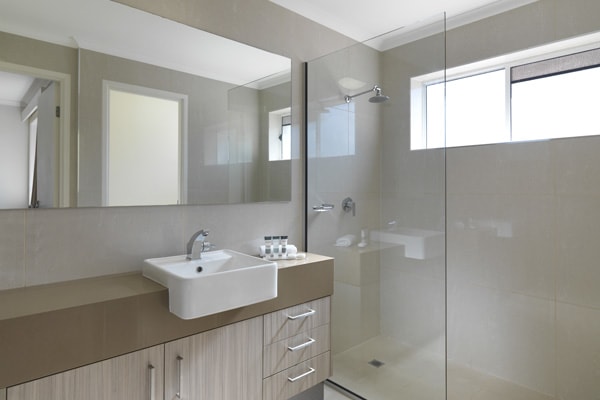 en suite bathroom with shower, toilet and clean towels in Executive King hotel room apartment at Oaks Oasis Resort in Caloundra on Sunshine Coast, Queensland, Australia