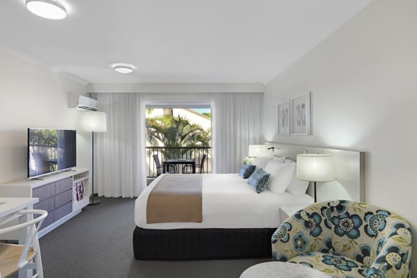 Caloundra accommodation with air conditioned master bedroom, TV and sliding glass doors leading out to private balcony of Executive Studio hotel apartment on Sunshine Coast