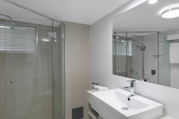 Executive Studio hotel apartment en suite bathroom with toilet, shower and large mirror at Oaks Oasis Resort in Caloundra on Sunshine Coast, Queensland, Australia