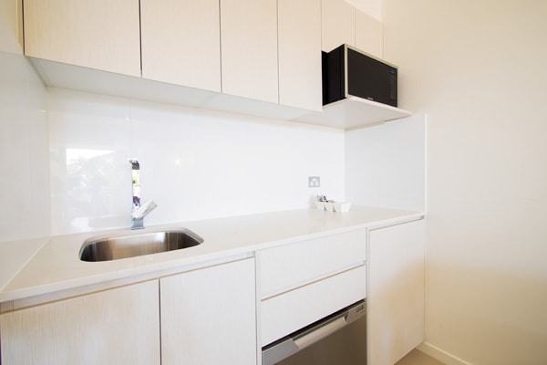 small kitchen with microwave, dishwasher, toaster and kettle in Executive King hotel room apartment at Oaks Oasis Resort in Caloundra