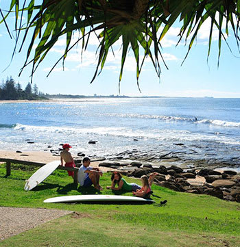 family relaxing on the beach with surfboards in Caloundra Sunshine Coast