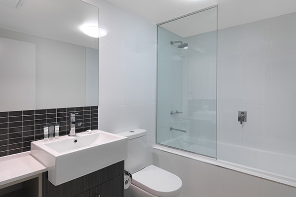 en suite bathroom of two bedroom apartment with big shower, bathtub and clean toilet at Oaks Rivermarque hotel in Mackay, Queensland, Australia