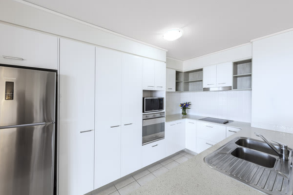 kitchen with microwave, fridge, oven and cupboards in one bedroom apartment at Oaks Seaforth Resort hotel, Sunshine Coast, Queensland, Australia