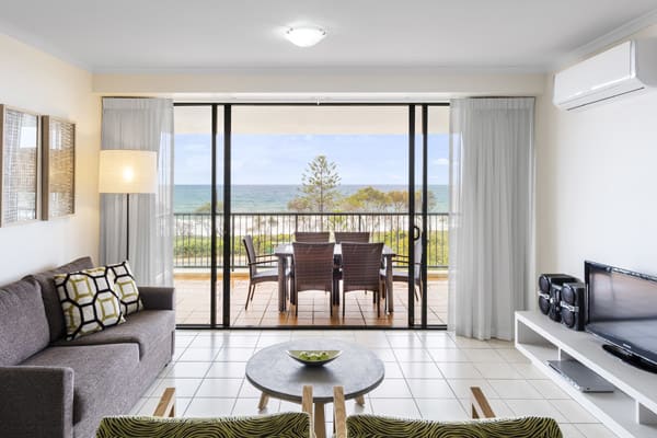 air conditioned living room with comfortable couches and private balcony outside with views of ocean and Sunshine Coast beach near Mooloolaba