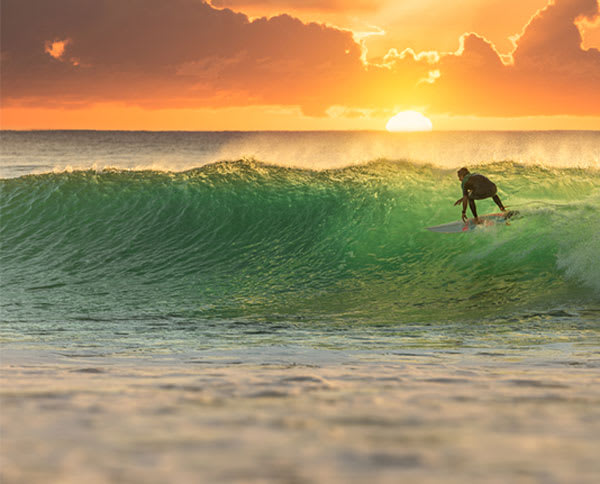 man surfing at sunset in Queensland with ocean in background