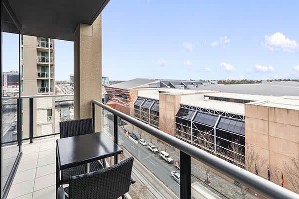 large balcony with black table and chairs with views of Adelaide city and blue sky in background