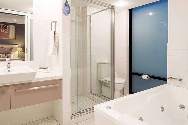 big spa bath in en suite bathroom with shower, toilet and large mirrors in 2 bedroom apartment near Adelaide Oval, perfect for sports lovers