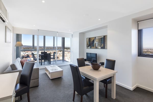 living room with couches, TV and private balcony in one bedroom apartment at iStay Precinct hotel on Morphett St in Adelaide city