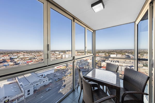 balcony at hotel Adelaide CBD with large windows, table, chairs and panoramic views of Adelaide city at iStay Precinct hotel near Adelaide Oval AFL stadium