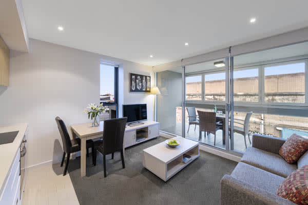 large living room with plenty of light, modern furniture, TV and private balcony in 2 bedroom apartment at iStay Precinct hotel in Adelaide city