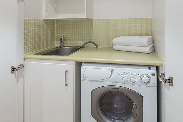 washing machine in laundry room of air conditioned 1 bedroom apartment at Oaks Liberty Towers hotel in Glenelg