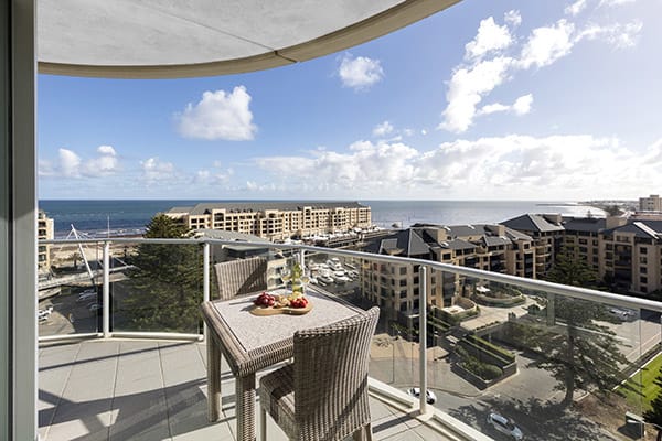 Glenelg hotels with huge balcony with vegan food on table and great views of ocean at family friendly 3 bedroom apartment at Oaks Liberty Towers hotel in Glenelg, South Australia