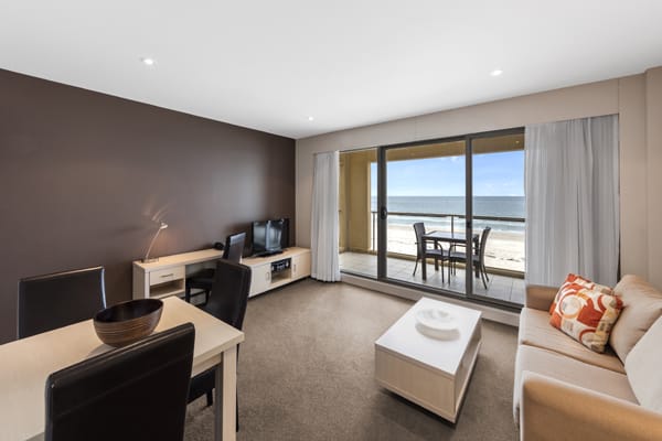 spacious living room with air con and wi-fi access leading out to big beachfront private balcony in 1 bedroom apartment at Oaks Plaza Pier hotel in Glenelg, South Australia